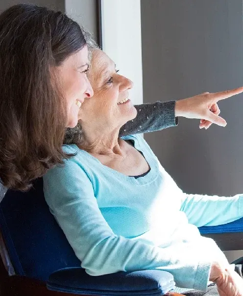 Acompañante y mujer mayor compartiendo un momento junto a la ventana